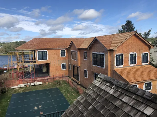 Two-story home with cedar-shingle roof, during construction